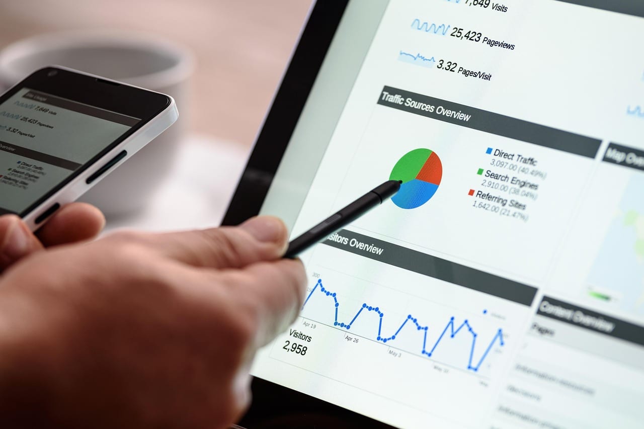 Mano con lápiz digital sobre una tableta que muestra un tablero de analítica con gráficos